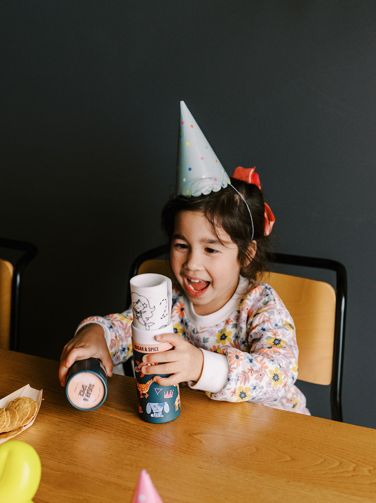 A girl or boy at a party with hat on opening her gift of a HeyDoodle silicone mini mat colouring in.