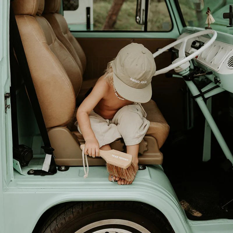 kid using Sande Kids sand brush to remove sand on feet
