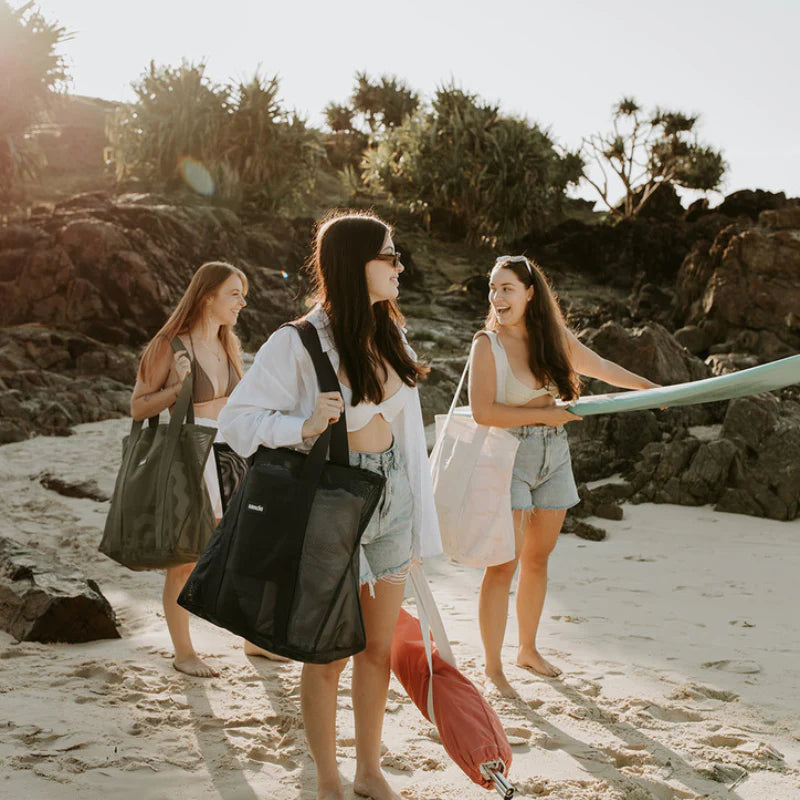 Girl on beach with friends carrying Sande Kids beach bag mini in navy.
