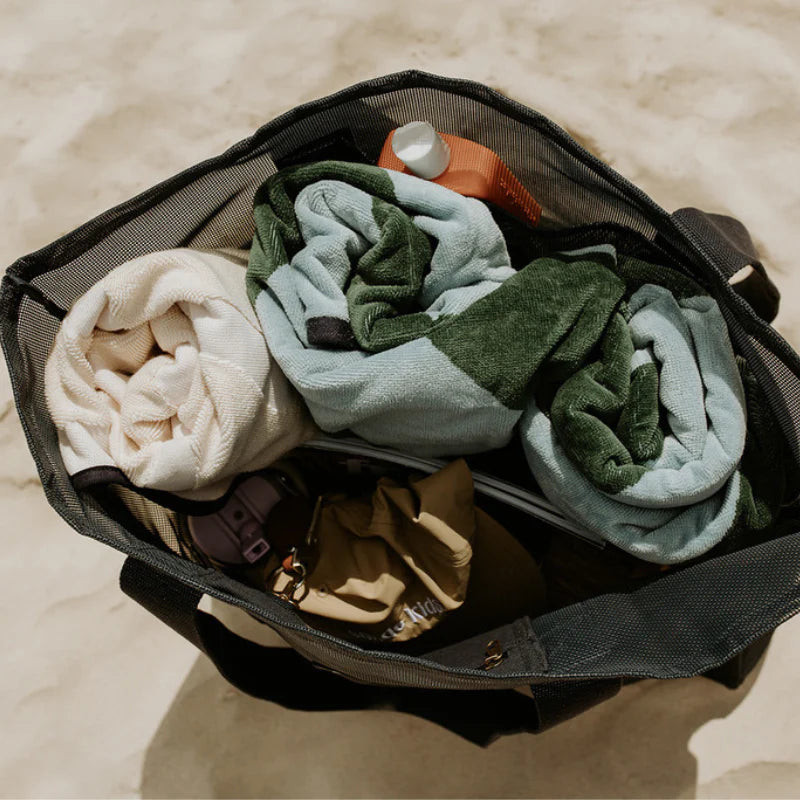 Sande Kids mesh beach or pool bag on sand full with towels, sunscreen, hats, drink bottles.