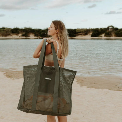 Mum on beach with large mesh beach bag.