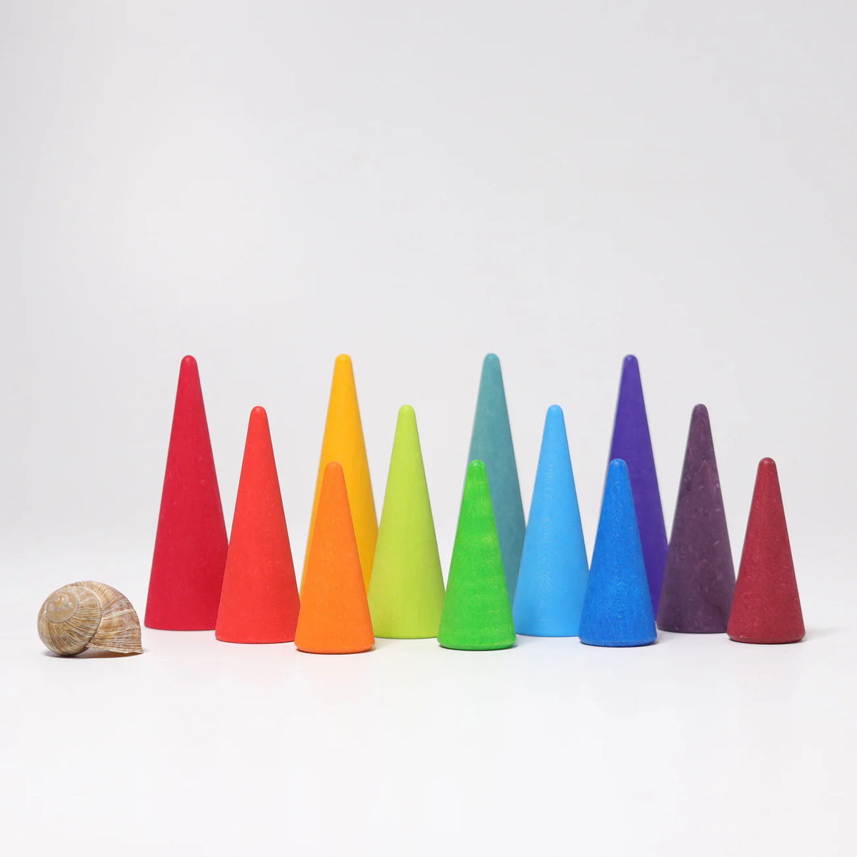 Grimms colourful wooden cones on a white background with a snail for scale.