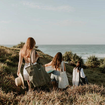 girl carrying shoulder mesh beach bag with friends walking to beach.