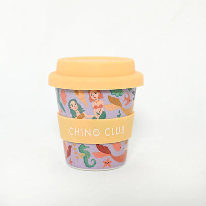 Mermaid baby chino cup for coffee or hot chocolate. Purple background with images of mermaids with yellow lid.